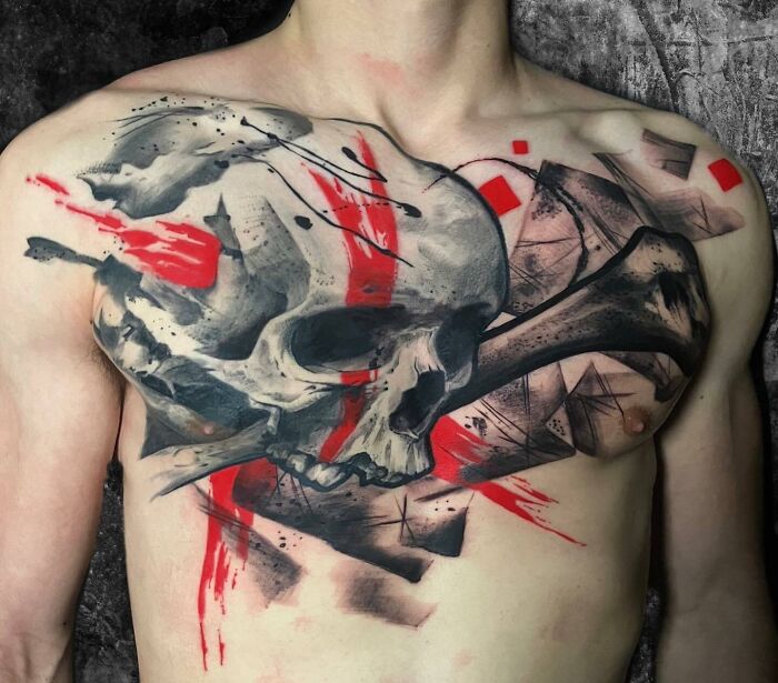 Chest with a bold Trash Polka tattoo depicting a skull and abstract red and black designs.