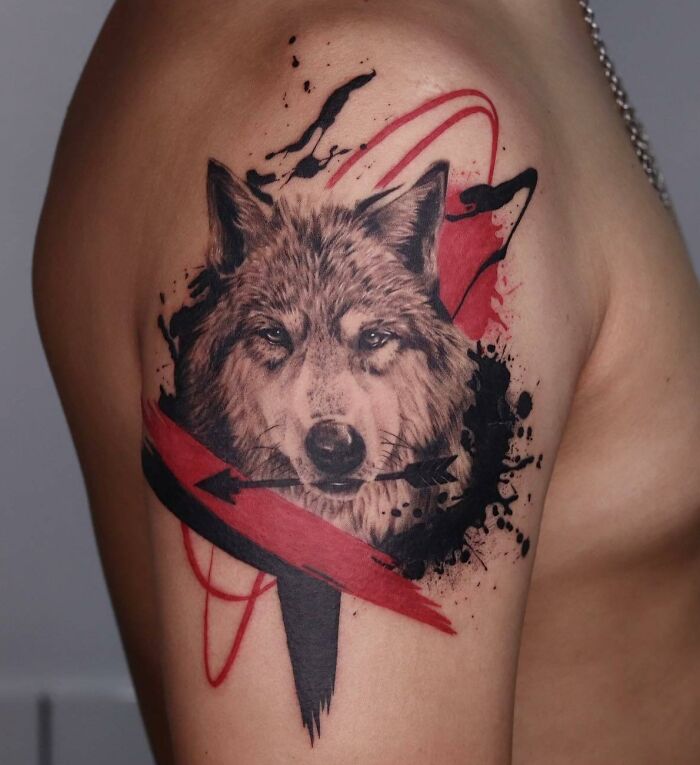 Wolf-themed Trash Polka tattoo design on upper arm, featuring bold red and black splashes.