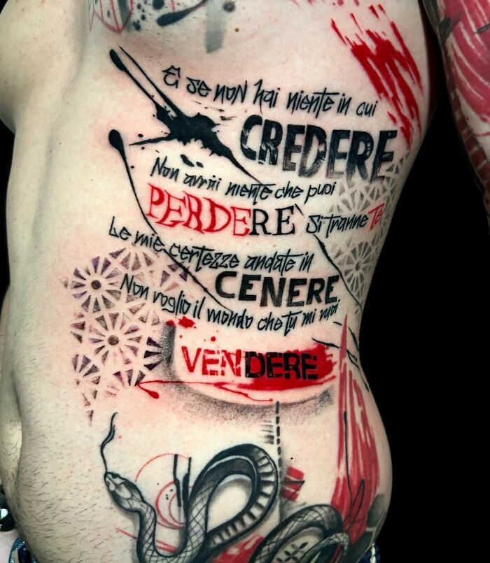 Trash Polka tattoo featuring Italian text with black and red ink, snake design, and splatter effects on the side of a torso.