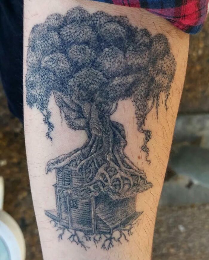 Tattoo of a majestic tree with a detailed house at its base, symbolizing the wonders of nature.
