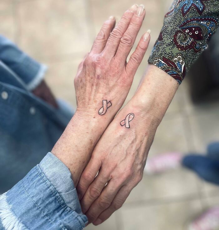 Two small hand tattoos in ribbon shapes on different wrists, showcasing delicate and minimalistic design.