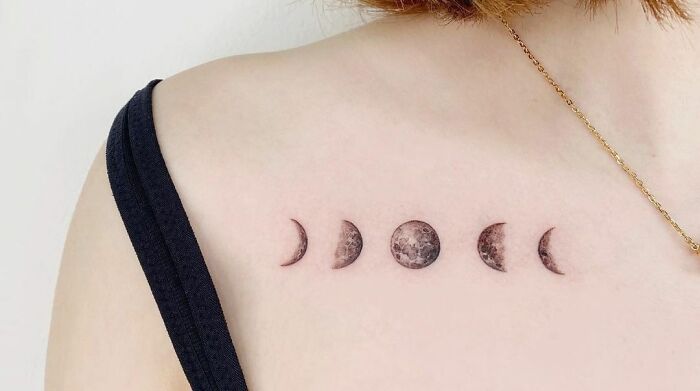 Collarbone tattoo of moon phases on a woman's shoulder, featuring intricate lunar design.
