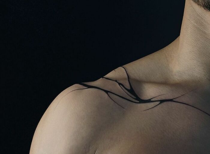 Abstract collarbone tattoo design on a person's shoulder.