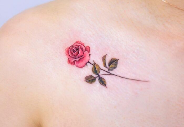 Rose tattoo on collarbone with delicate leaves, showcasing stunning design for men and women.