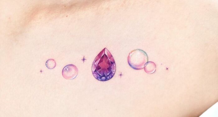 Colorful collarbone tattoo featuring a gem and bubbles, showcasing unique tattoo design for men and women.