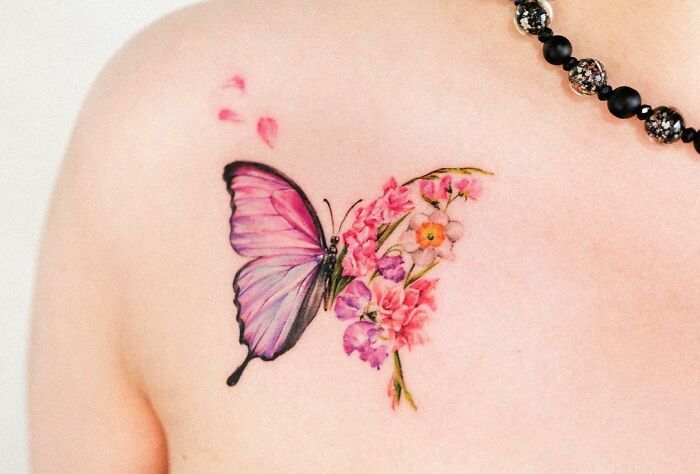 Colorful butterfly and flowers tattoo on a collarbone.