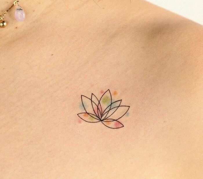 Minimalist lotus collarbone tattoo with subtle watercolor accents.