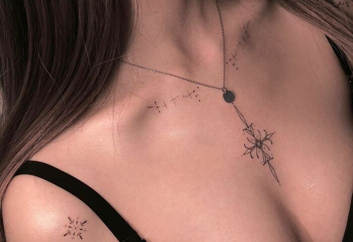 Collarbone tattoo featuring delicate floral design with a black ink pattern on a woman's shoulder and neckline.
