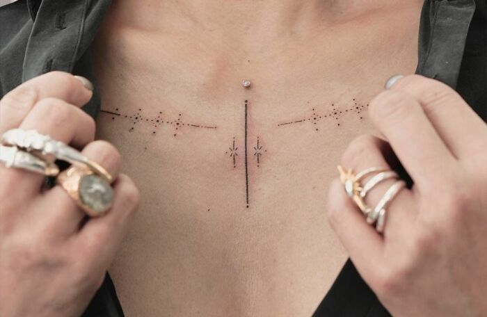 Intricate collarbone tattoo design on a person's chest, featuring geometric and dot patterns.