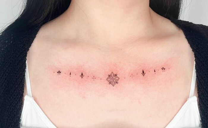 Collarbone tattoo with delicate symmetrical designs for men and women.