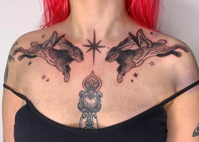 Collarbone tattoos featuring flying rabbits and stars on a woman with red hair.