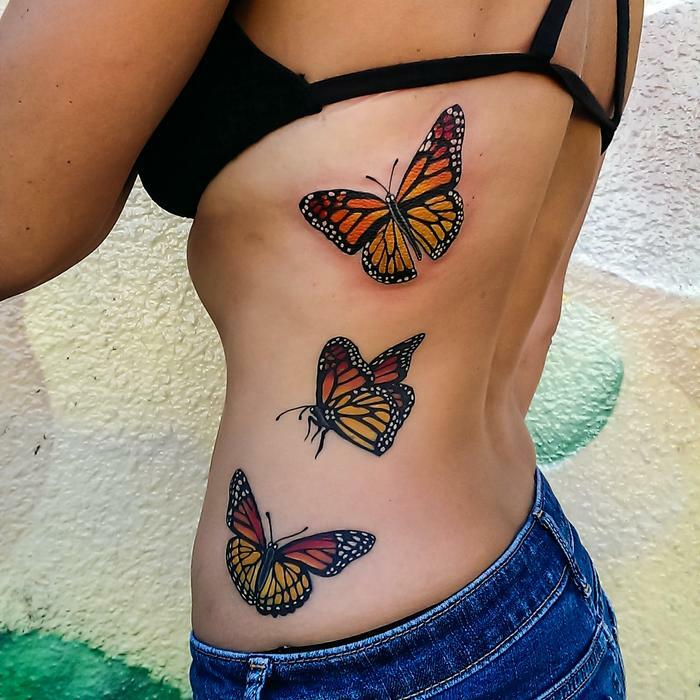 Colorful butterfly tattoos on a person's side, showcasing vibrant and detailed designs.