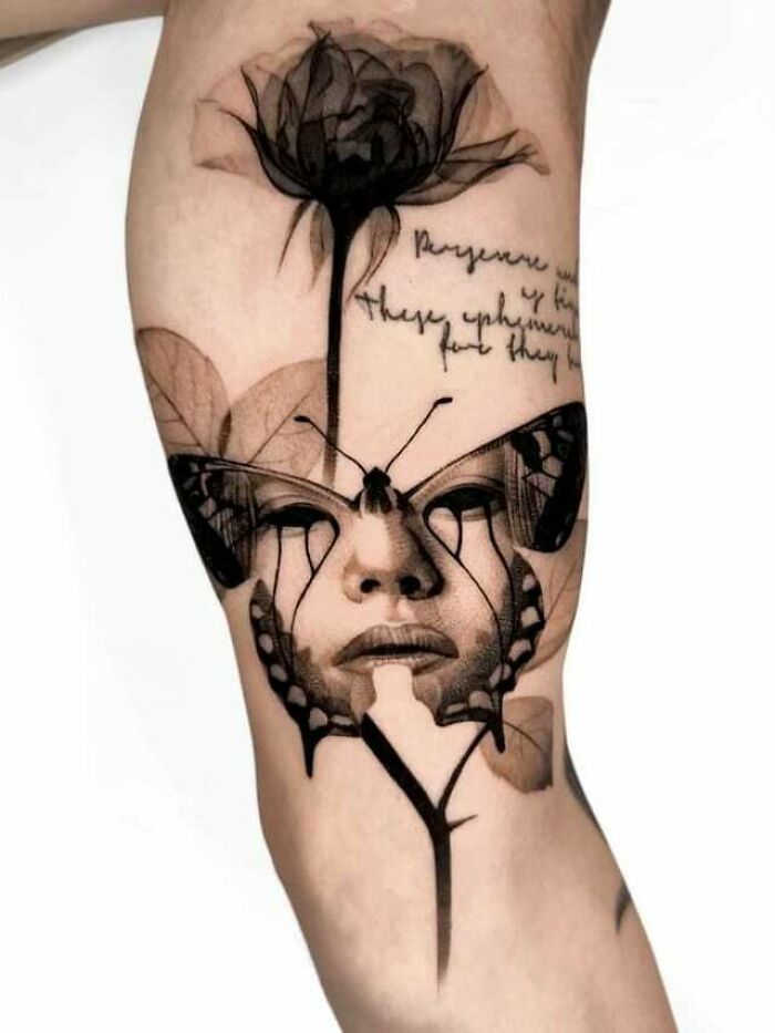 Artistic butterfly tattoo with a face and floral design on the arm.
