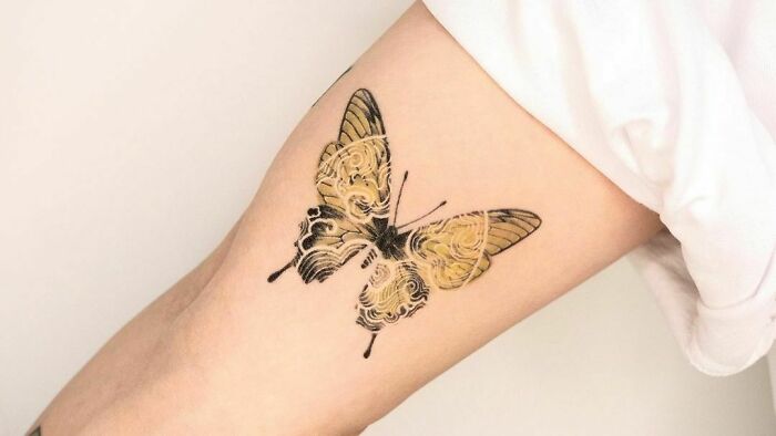 Colorful butterfly tattoo on arm, showcasing intricate and fun design.