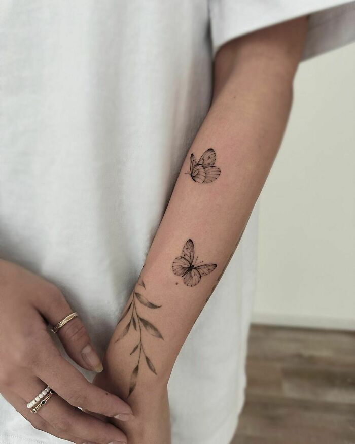Minimalistic butterfly tattoos on forearm, showcasing delicate and elegant design.