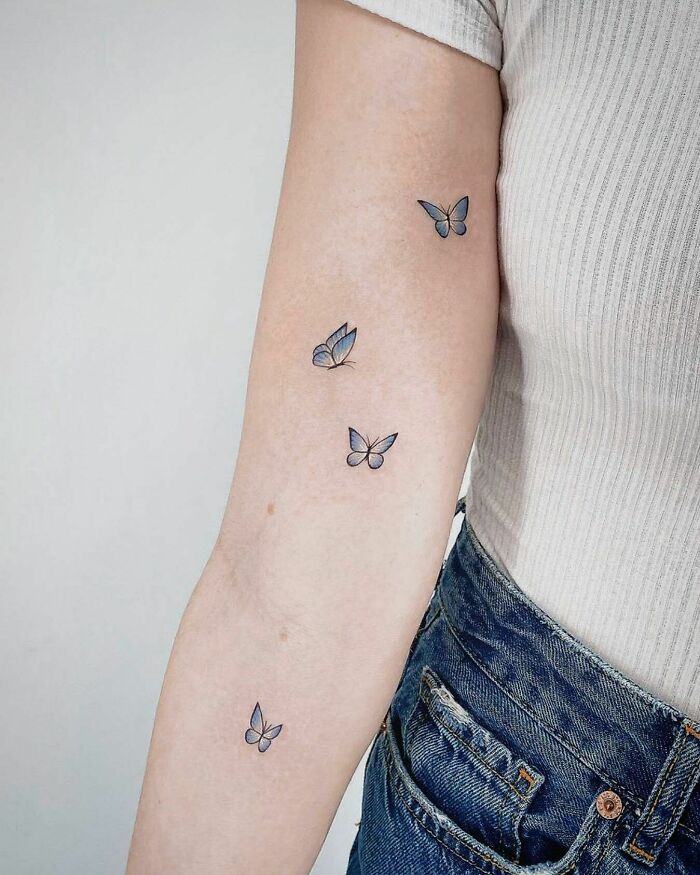 Four colorful butterfly tattoos elegantly placed on a person's forearm, showcasing vibrant and fun designs.