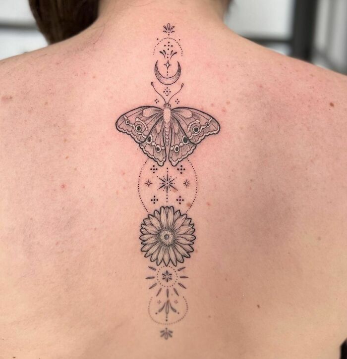 Intricate butterfly tattoo design featuring celestial and floral elements on the back.