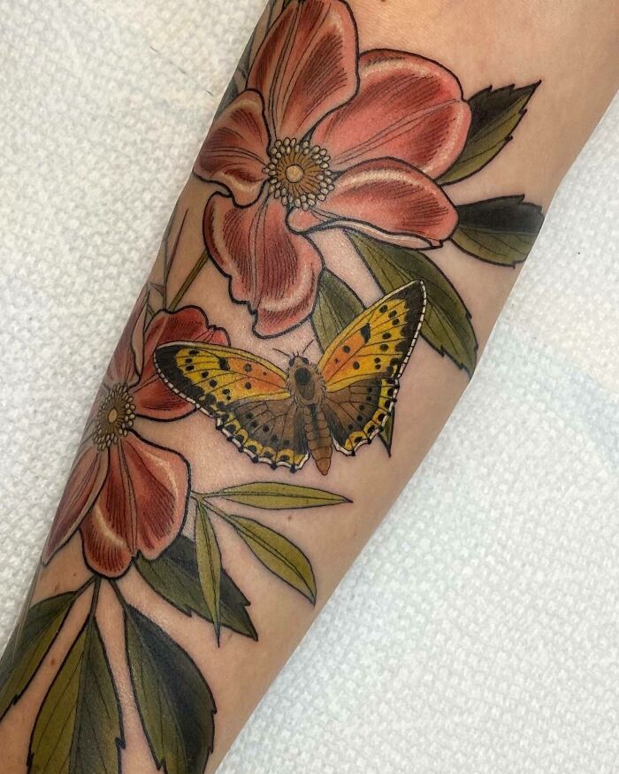 Colorful butterfly tattoo with flowers on forearm, showcasing vibrant and fun design.