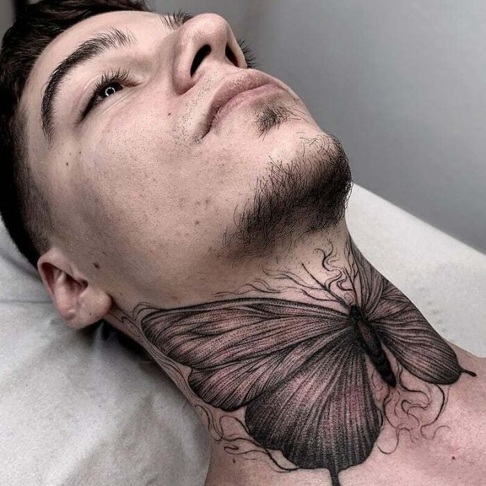 Butterfly tattoo on a person's neck, featuring detailed black ink designs, showcasing creativity and style.
