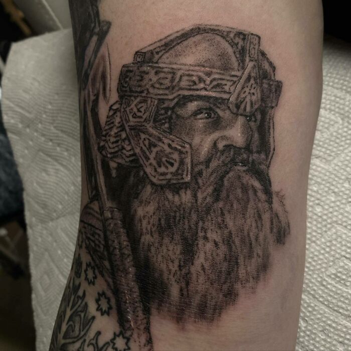 Detailed Lord of the Rings tattoo depicting a helmeted character with a beard on an arm.