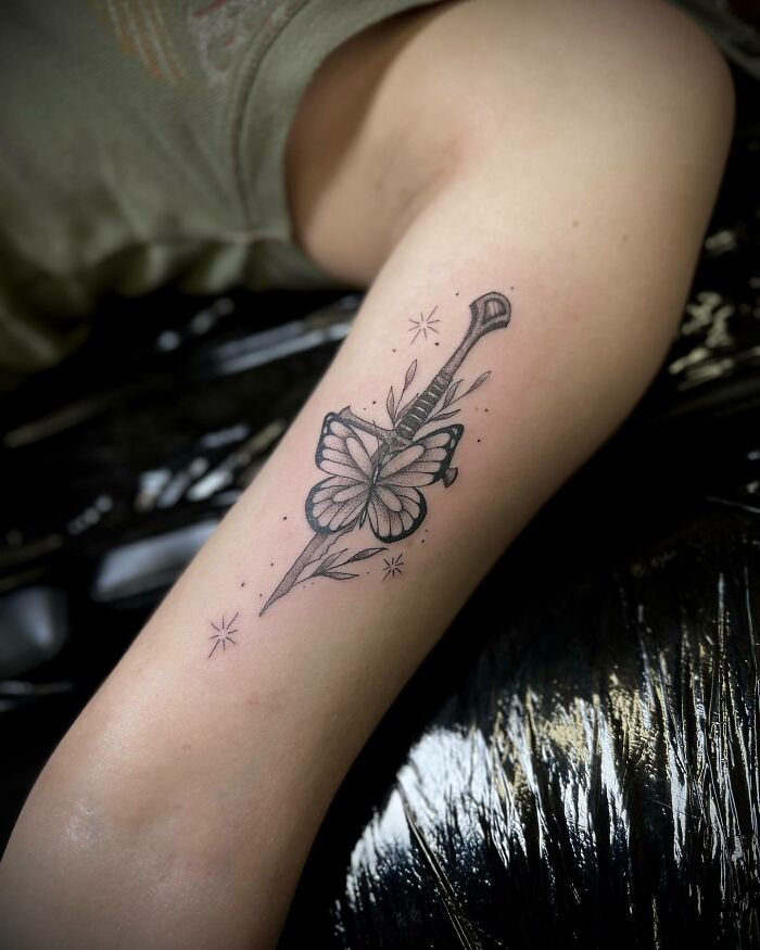 Arm with a Lord of the Rings tattoo featuring a sword and a butterfly design.