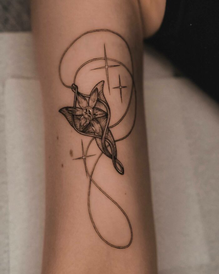 Elvish flower and star "Lord of the Rings" tattoo on forearm with intricate linework.
