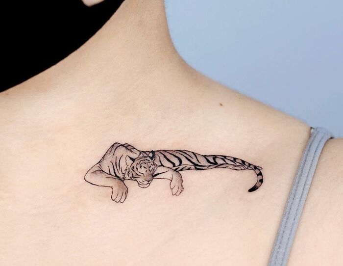 Tiger design collarbone tattoo on person wearing a tank top.