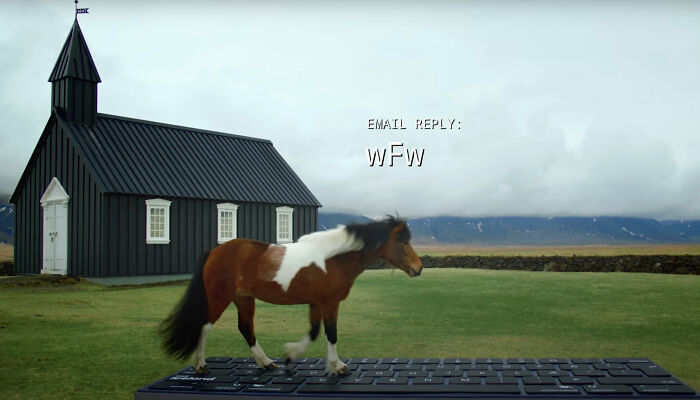 Icelandic horse walking on a giant keyboard near a black church, generating an email reply.