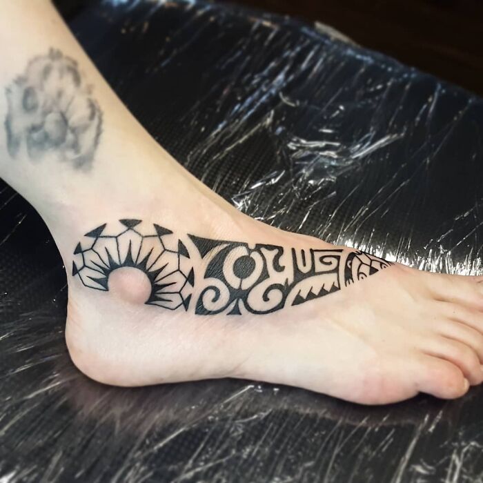 Foot with a black tribal tattoo featuring geometric patterns.