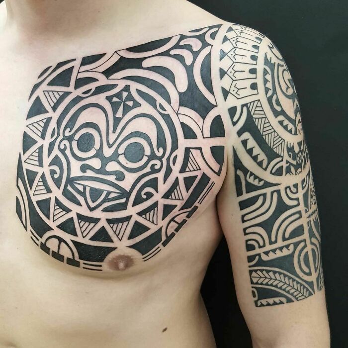 A detailed tribal tattoo design covering a man's chest and arm.