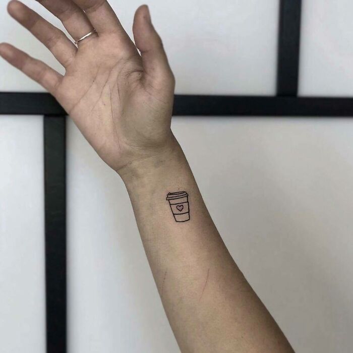 Minimalist wrist tattoo of a coffee cup with a heart design.