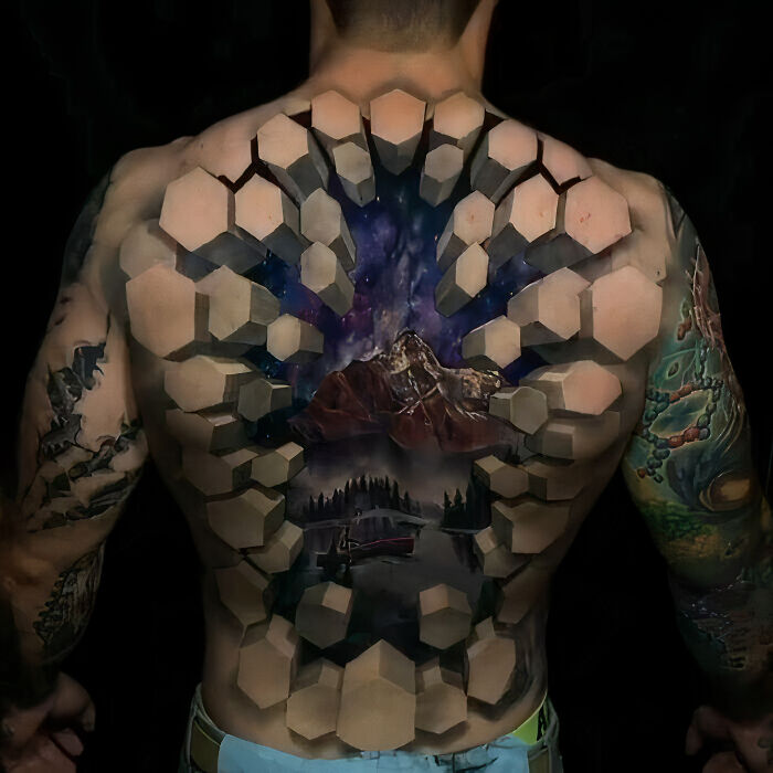 Back showcasing an epic optical illusion tattoo design of a 3D landscape with mountains and geometric shapes.