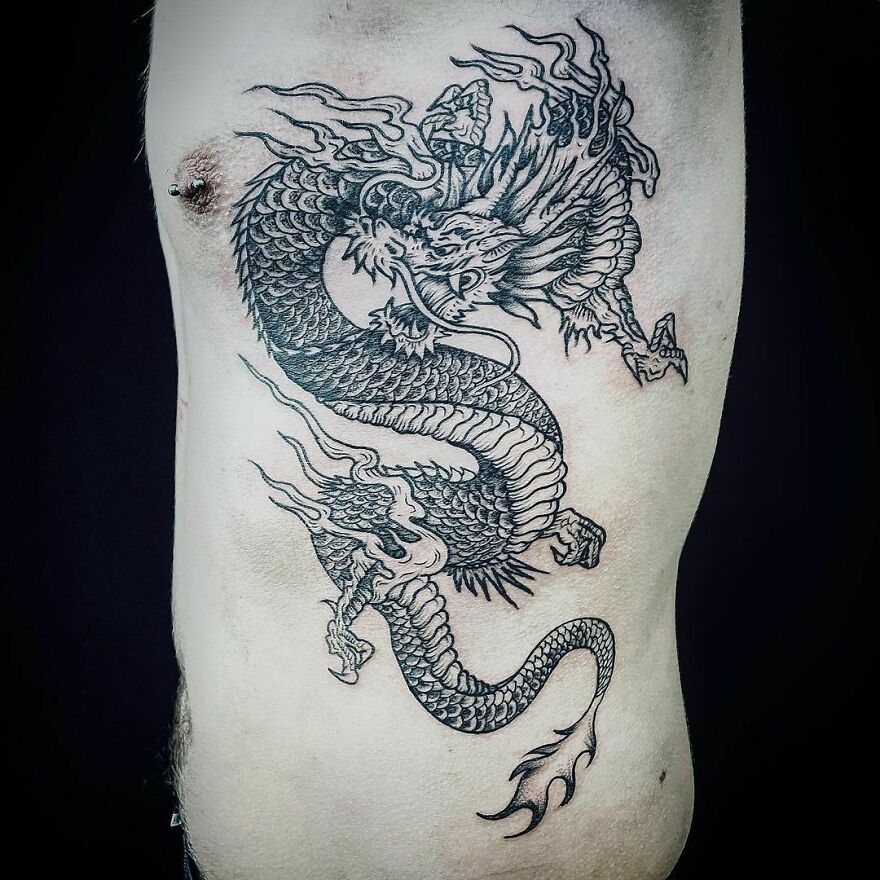 Intricate dragon tattoo design on a person's ribcage, showcasing detailed scales and fierce expression.