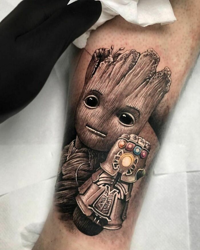 Pop culture tattoo of a character holding a glove with colorful stones, detailed and realistic design on an arm.