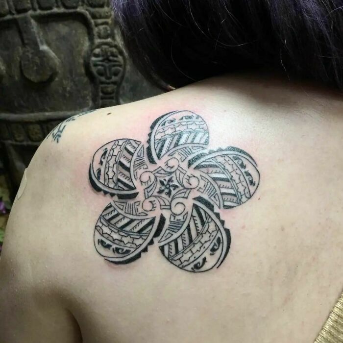 Intricate tribal tattoo design on shoulder, featuring a geometric flower pattern.
