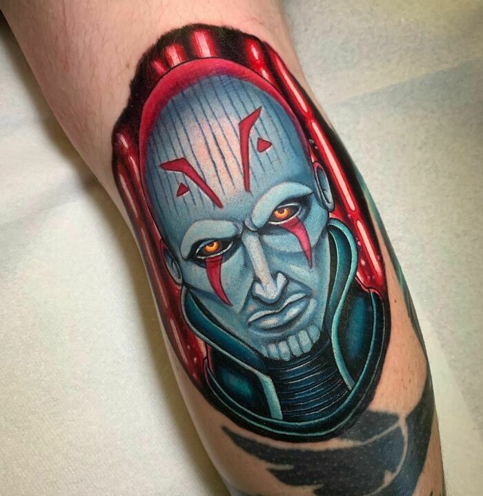 Colorful pop culture tattoo of a sci-fi character with red markings and yellow eyes.