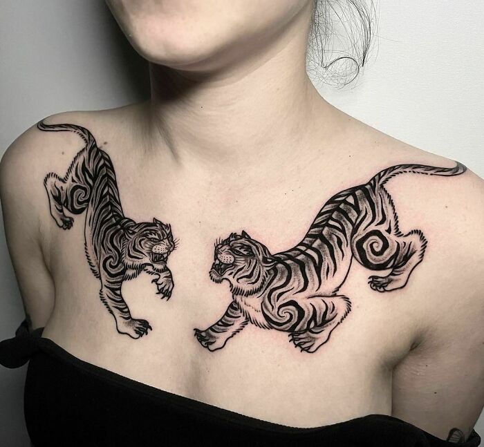 Tribal tiger tattoos on a woman's chest, showcasing intricate designs and bold lines.