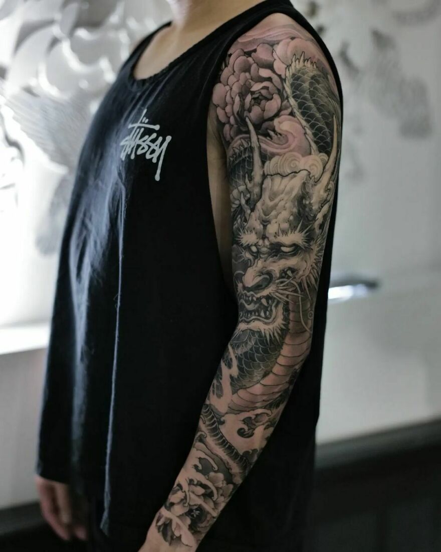 Person with detailed dragon tattoo sleeve wearing a black tank top.
