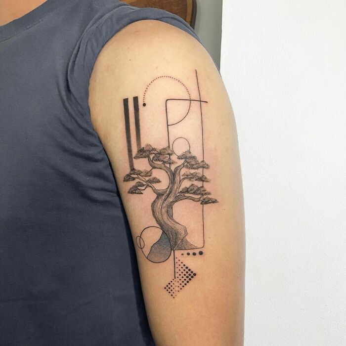 Tattoo of a tree with geometric designs on a person's upper arm.
