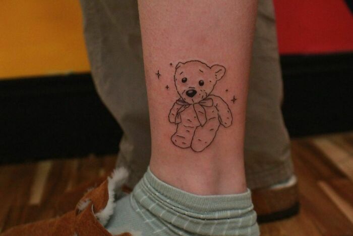 Ankle tattoo of a teddy bear with stars on skin, showcasing tattoo care and inspiration.