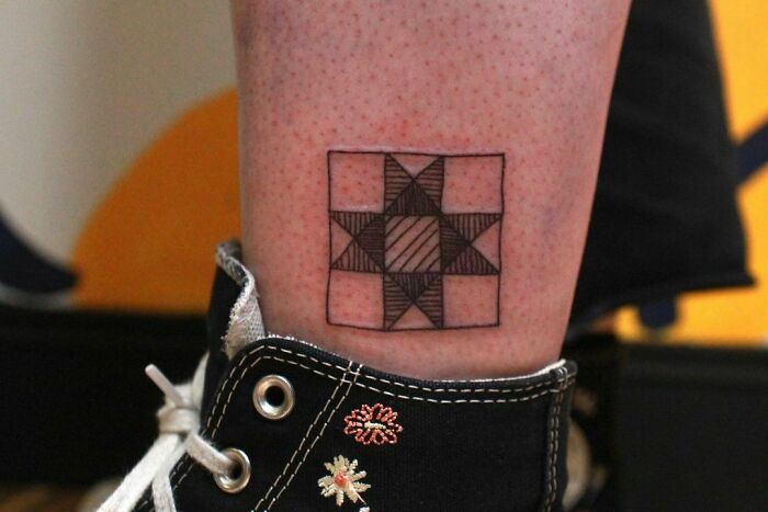 Ankle tattoo with geometric star design, wearing black canvas shoe.