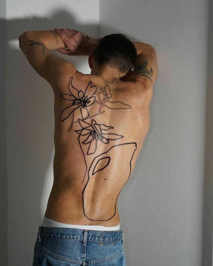 Tattoo artist's viral back piece with abstract floral design and bold lines, drawing widespread attention online.
