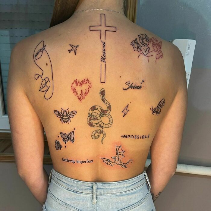 Person with patchwork tattoo designs, including a cross, snake, butterflies, and inspirational words on their back.