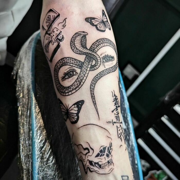 Patchwork tattoo on forearm featuring a snake, eyes, butterfly, lighter, and skull design.