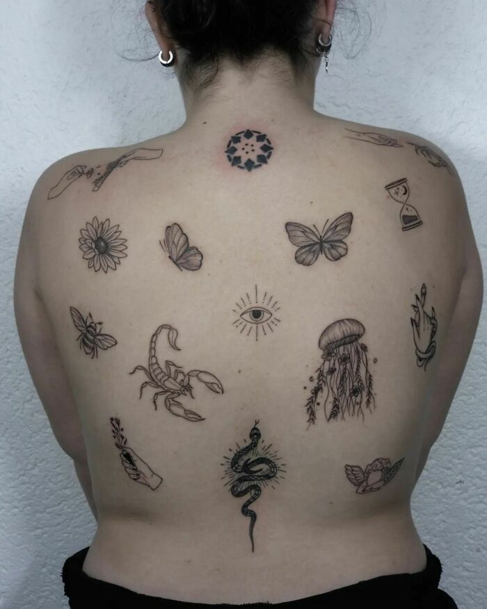 Person's back with multiple patchwork tattoos, including a scorpion, butterflies, eye, snake, and jellyfish.