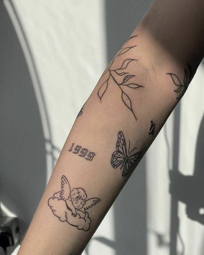 Patchwork tattoo featuring leaves, numbers, a butterfly, and a cherub on an arm, showcasing unique, modern design elements.