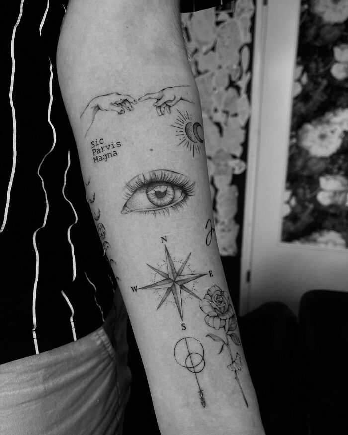 Tattoo sleeve featuring an eye, compass, rose, and celestial symbols in intricate patchwork design.