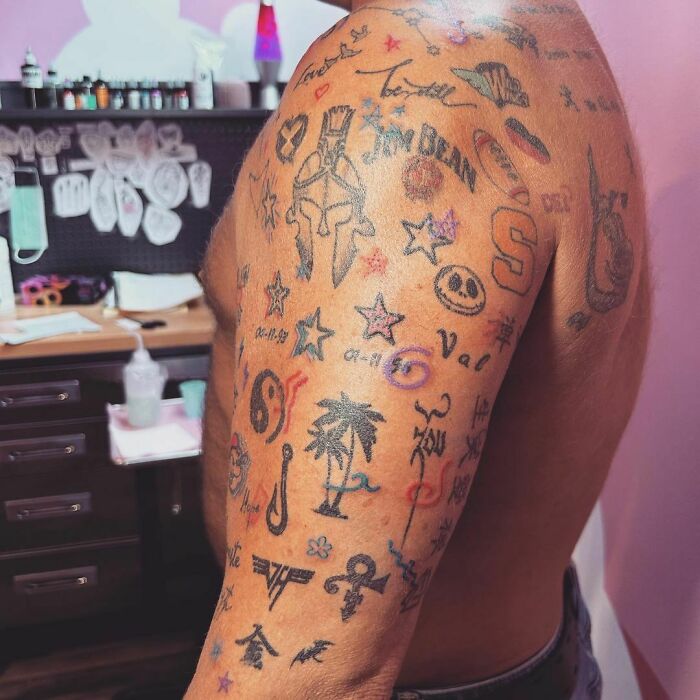 Arm showcasing patchwork tattoo designs with various symbols and icons in a tattoo studio.