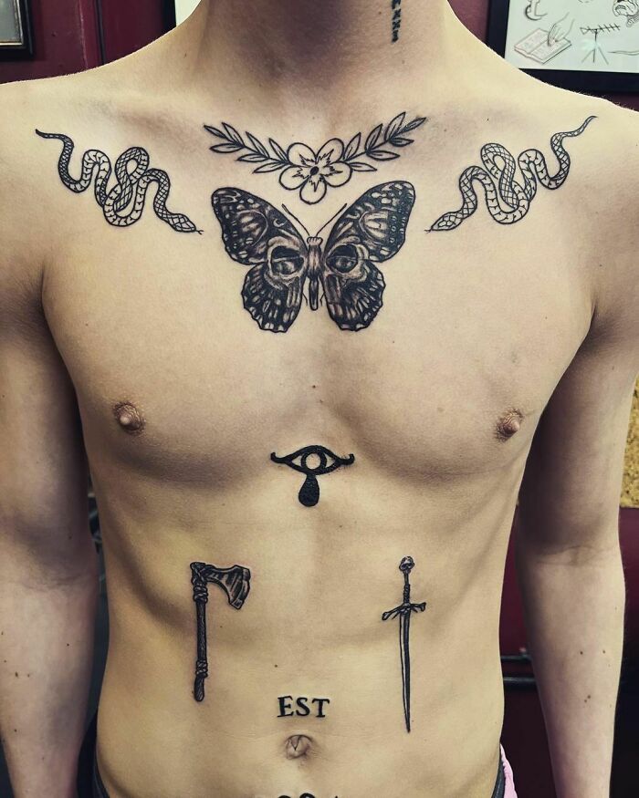 Chest with intricate patchwork tattoos, including a butterfly, snakes, an eye, an axe, and a sword, in a modern design.