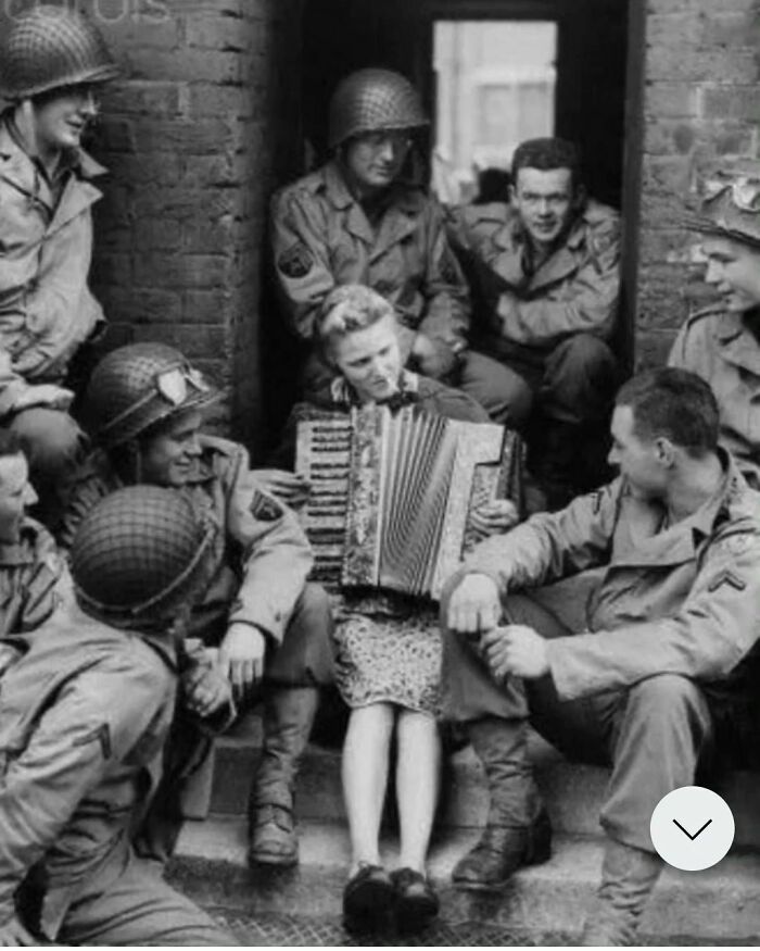 Mrs. Hale, The Wife Of A British Soldier, Plays The Accordion Outside Her House For A Group Of American Soldiers In England, 1944